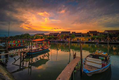 Boats moored at harbor during sunset