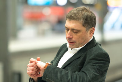 Thoughtful businessman checking time standing at railroad station platform