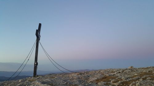 Rope on rock by sea against clear blue sky