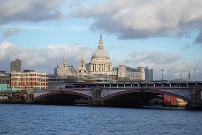Arch bridge over river against cloudy sky