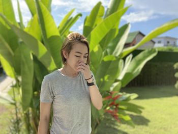 An asian woman with her short blond hair standing in the garden with strong sunshine. 