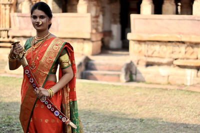 Portrait of young woman standing against building