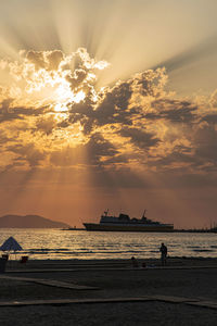 Silhouette people on beach against sky during sunset