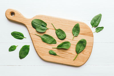 Wooden cutting board with fresh green salad leaves of spinach on white background. healthy eating