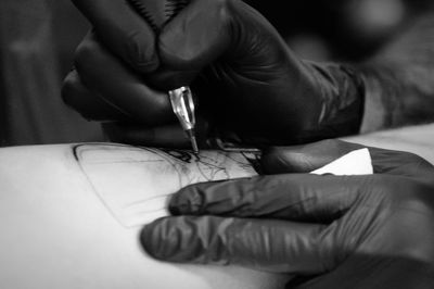 Close-up of hands making tattoo on man