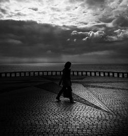 Silhouette of woman against cloudy sky at sunset