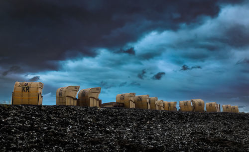 Hooded beach chairs against dramatic sky