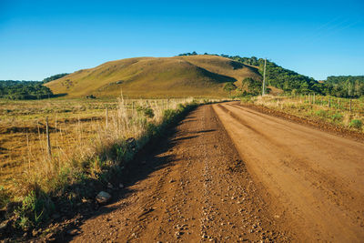 Deserted dirt road passing through rural lowlands with green hills near cambará do sul. brazil.