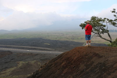 Rear view of man standing on mountain against sky