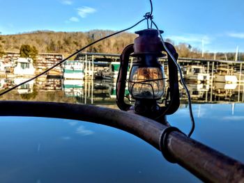 Bicycle hanging on boat in river against sky