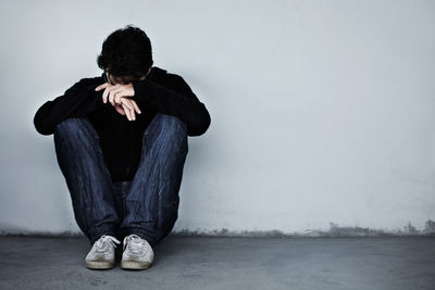 A man looking sad and depressed. a young guy sitting on the floor. mental health and emotion