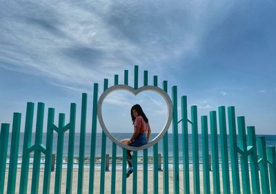 Digital composite image of man sitting against sky