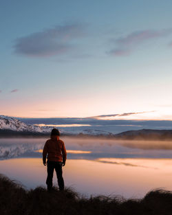 Rear view of man standing on mountain against sky