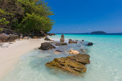 Scenic view of rocks in sea against blue sky