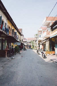 Road amidst buildings in city against clear sky