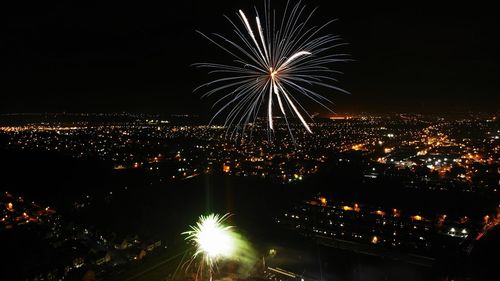 Firework display over illuminated buildings in city at night