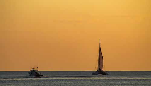 Sailboat sailing on sea against sky during sunset