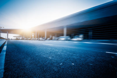 Empty road against clear blue sky in city