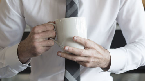 Midsection of man holding coffee cup