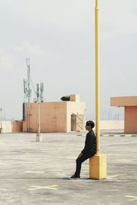 Side view of man sitting on a post 