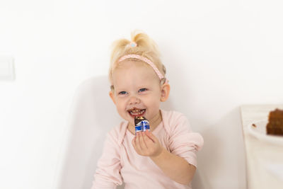 Portrait of cute girl eating food on bed at home