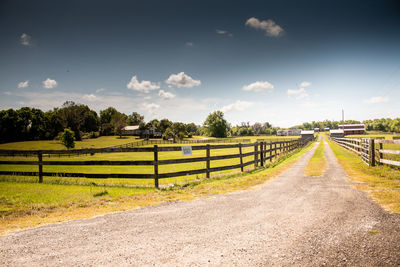 Road amidst field against sky