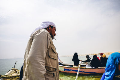 Side view of man standing on sea against sky