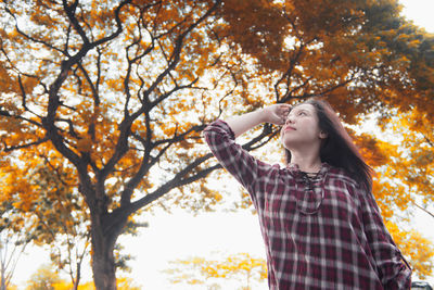 Low angle view of woman standing against tree