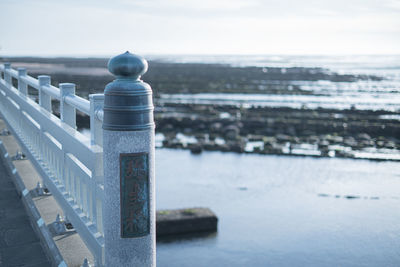 Railing by sea against sky