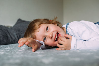 Little cute child is lying and having fun at home on sofa, smiling and laughing
