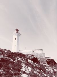 Low angle view of lighthouse by building against sky