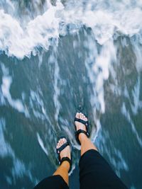 Low section of person standing on rock in sea