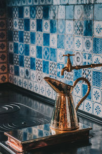 Close-up of container under faucet against wall at home