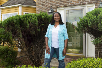 Smiling african-american woman standing in front of her house