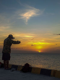 Man standing on beach against sky during sunset