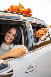 Portrait of smiling woman sitting in car with dogs