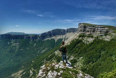 Rear view of man standing on rock against sky