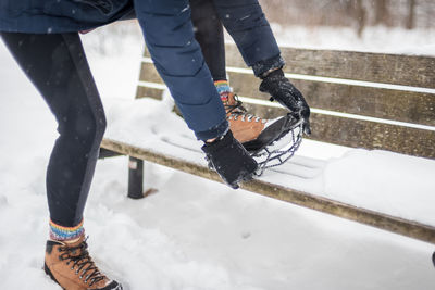 Low section of woman wearing shoe on bench during winter