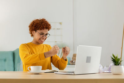 Young woman using laptop while sitting at desk in office