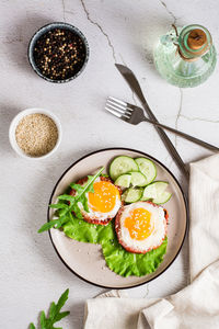 Eggs baked in tomato, arugula leaves and cucumber on a plate on the table. homemade lunch. 