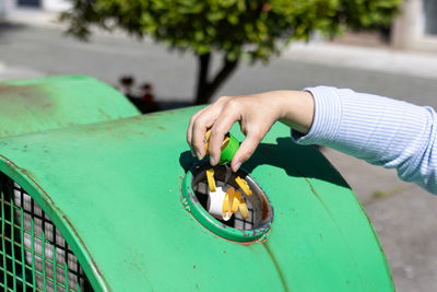 Female hand throwing plastic bottle caps into an urban recycling bin. recycle and reuse concept 