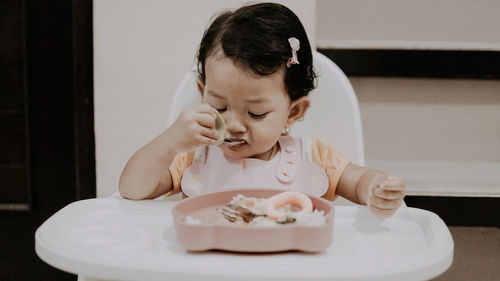 Potrait of baby girl eating food at home