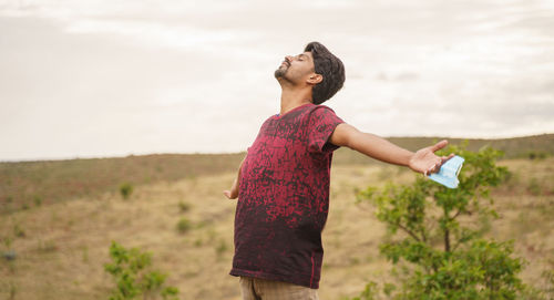Side view of woman standing on field against sky