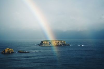 Scenic view of rainbow over sea against sky