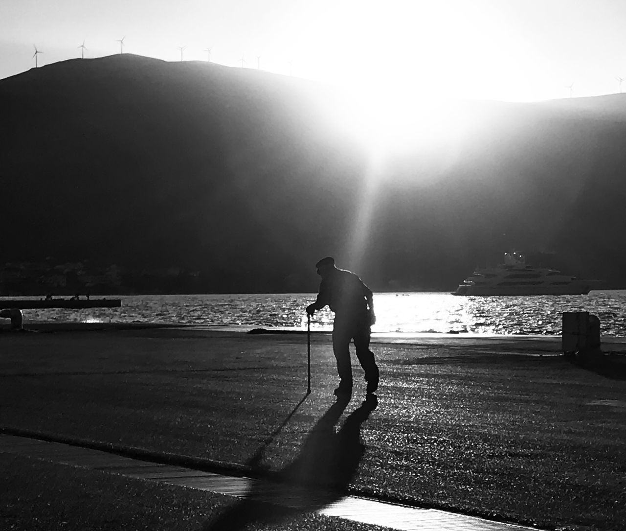 SILHOUETTE MAN WALKING ON SHORE AGAINST SEA