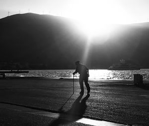 Silhouette man walking on shore against sky