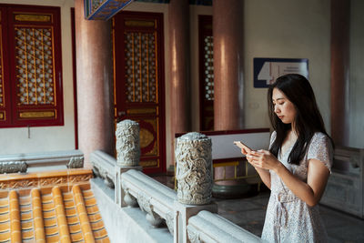 Woman holding mobile phone in room