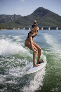 Side view of shirtless man in sea against mountain