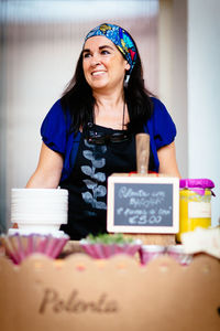 Happy female vendor standing by food stall at market