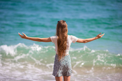 Rear view of woman standing at beach